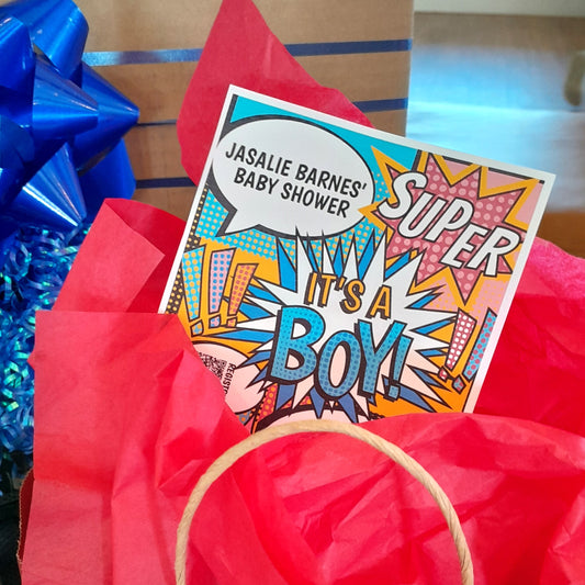 Baby shower gift bag with a 'Super It's a Boy' card on red tissue paper.